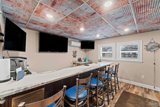 bar featuring light wood-type flooring and a wall mounted AC