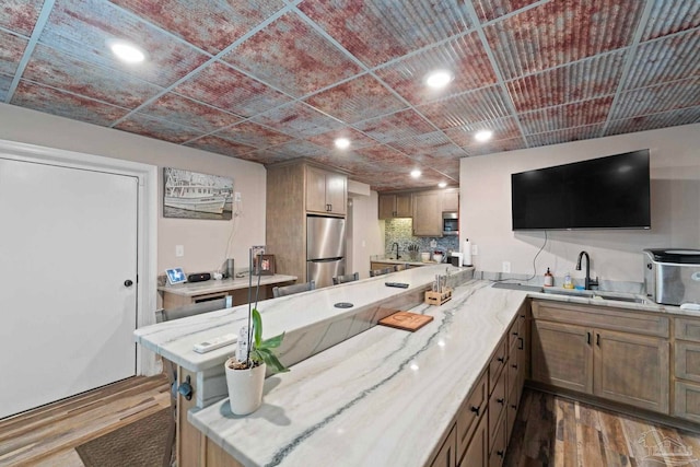 kitchen with kitchen peninsula, stainless steel appliances, tasteful backsplash, dark hardwood / wood-style flooring, and sink