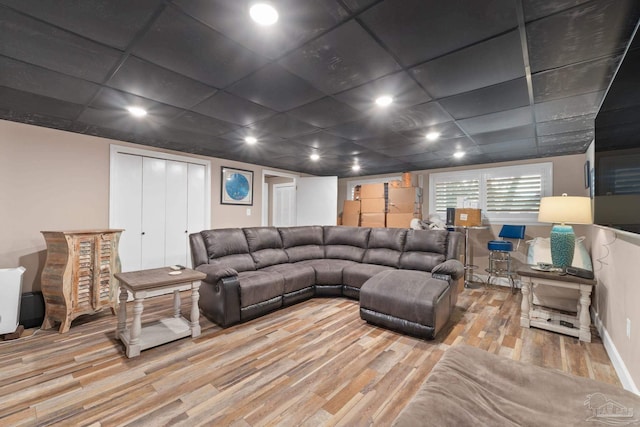 living room with a drop ceiling and wood-type flooring