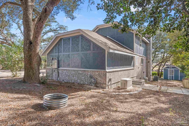 rear view of property featuring a storage unit and central AC