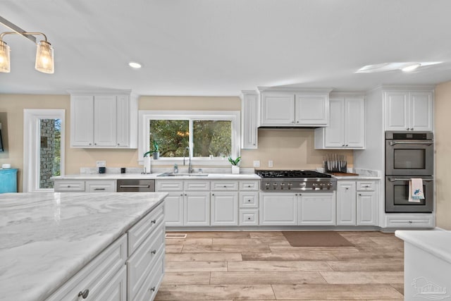 kitchen with appliances with stainless steel finishes, hanging light fixtures, white cabinets, and sink