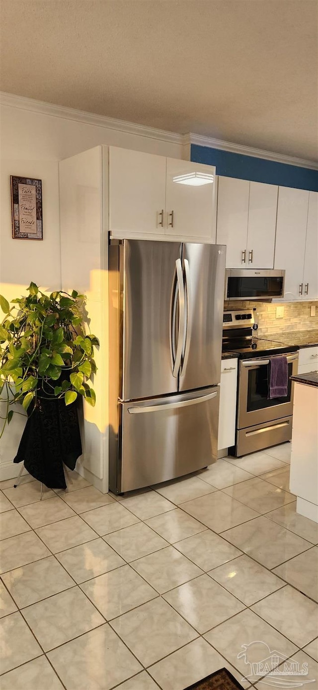 kitchen featuring ventilation hood, white cabinets, stainless steel appliances, light tile patterned flooring, and ornamental molding