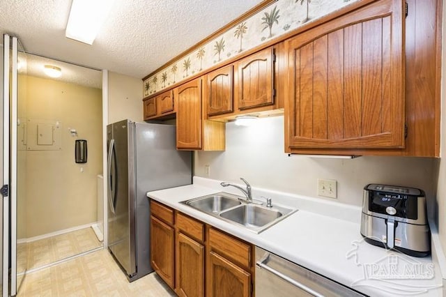 2299 Scenic Hwy Unit T7, Pensacola, FL 32503 - kitchen with a textured ceiling, a sink, light countertops, brown cabinetry, and freestanding refrigerator