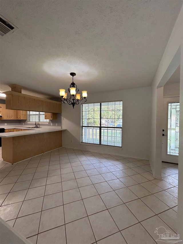 interior space with a chandelier, pendant lighting, kitchen peninsula, light tile patterned floors, and a textured ceiling