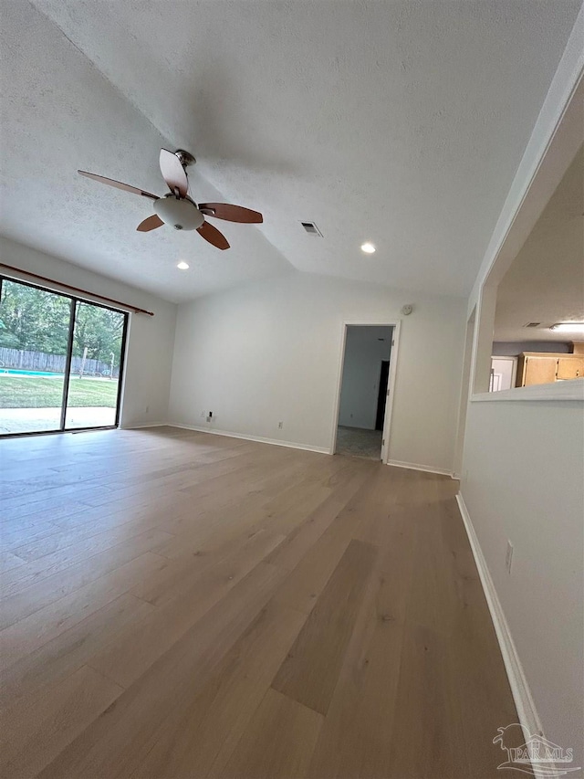 spare room with vaulted ceiling, ceiling fan, hardwood / wood-style floors, and a textured ceiling