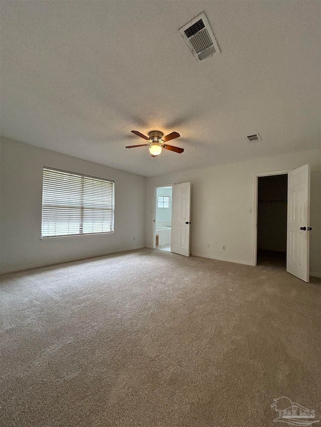 empty room featuring ceiling fan, a textured ceiling, and carpet flooring