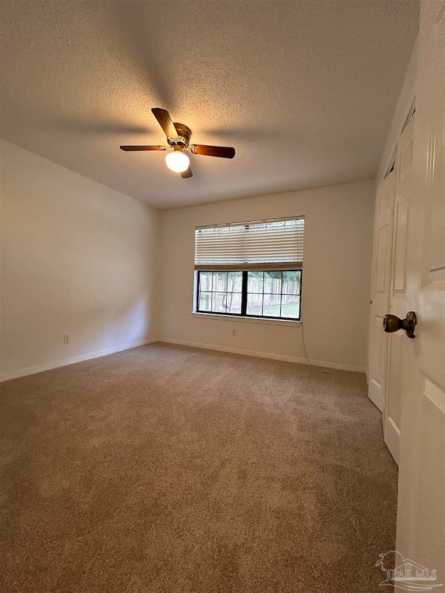 carpeted empty room with ceiling fan and a textured ceiling