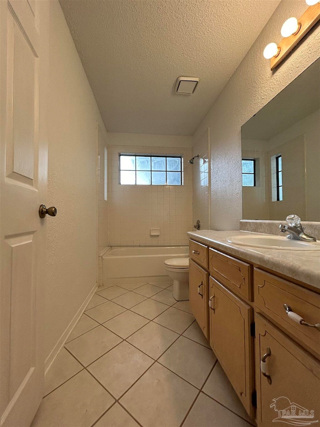 full bathroom with vanity, tiled shower / bath combo, tile patterned flooring, toilet, and a textured ceiling