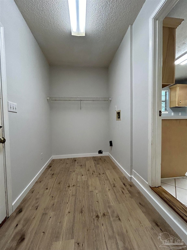 laundry room with light wood-type flooring, washer hookup, and a textured ceiling