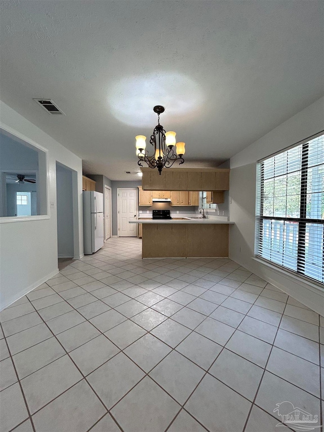 kitchen featuring sink, kitchen peninsula, pendant lighting, white fridge, and light tile patterned floors