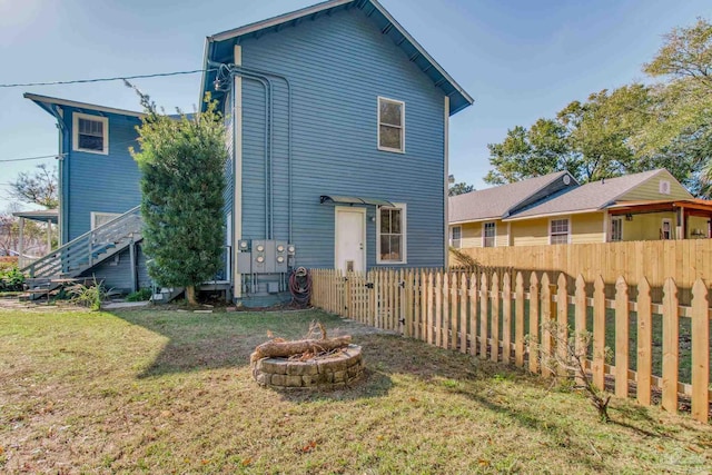 rear view of house with a yard and a fire pit