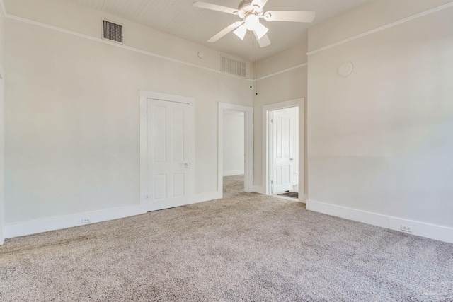 empty room with carpet, ceiling fan, and a towering ceiling