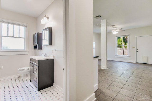 bathroom with ceiling fan, toilet, vanity, and a wealth of natural light