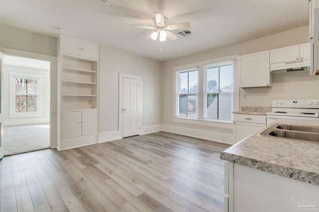 kitchen with white cabinets, electric range, sink, and a wealth of natural light