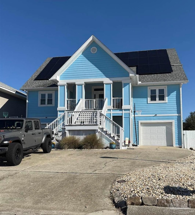 view of front facade featuring roof mounted solar panels, a porch, an attached garage, stairway, and concrete driveway