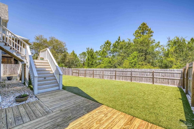 deck with a lawn, a fenced backyard, and stairway