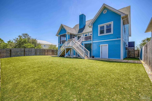 back of property with stairs, a yard, a fenced backyard, and a chimney