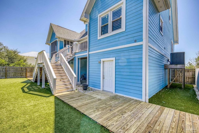 back of property featuring a fenced backyard, stairway, a wooden deck, and a lawn