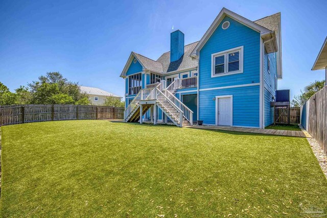rear view of property featuring a yard, a chimney, a fenced backyard, and stairs