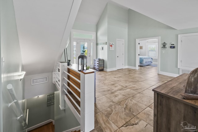 foyer with high vaulted ceiling, visible vents, and baseboards