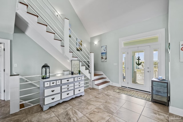 foyer with baseboards, stairway, and lofted ceiling