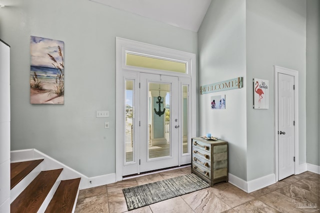 foyer featuring high vaulted ceiling, stairway, and baseboards