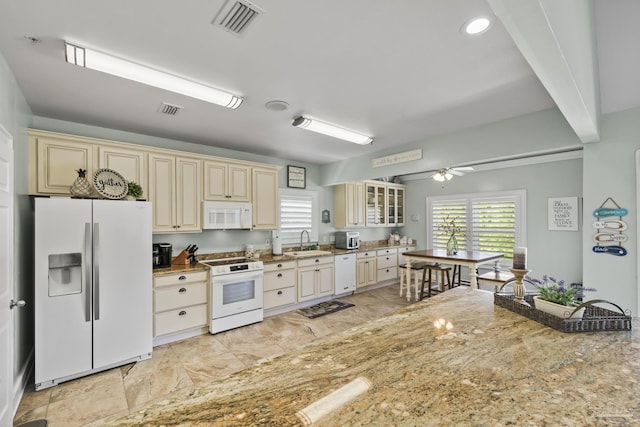 kitchen with white appliances, a sink, cream cabinets, and a healthy amount of sunlight