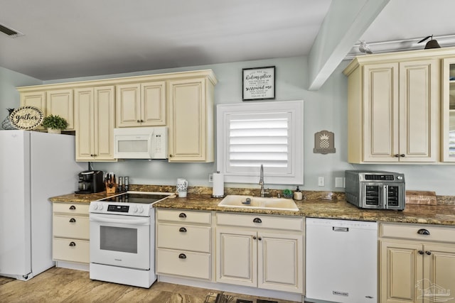 kitchen featuring white appliances, visible vents, a sink, and cream cabinets