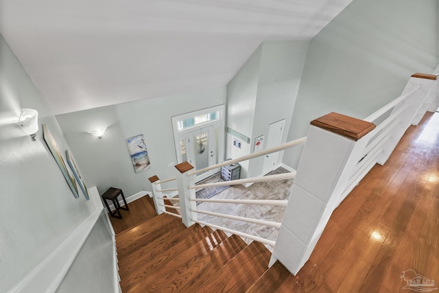 stairs featuring hardwood / wood-style flooring and lofted ceiling