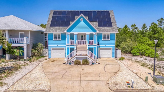 coastal home with a garage, driveway, covered porch, and stairway