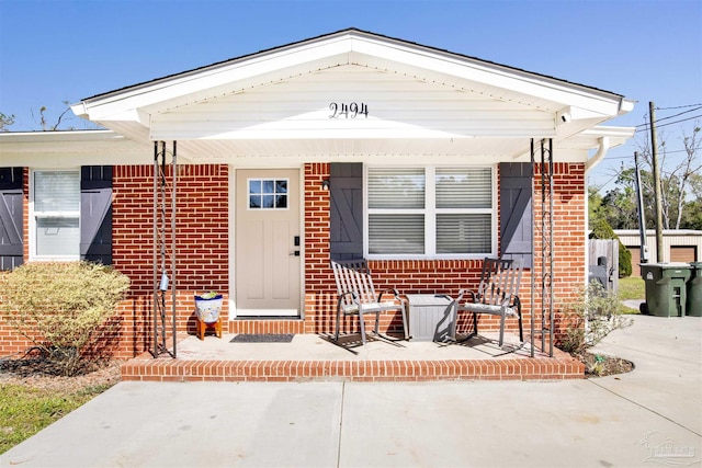 property entrance featuring brick siding and covered porch