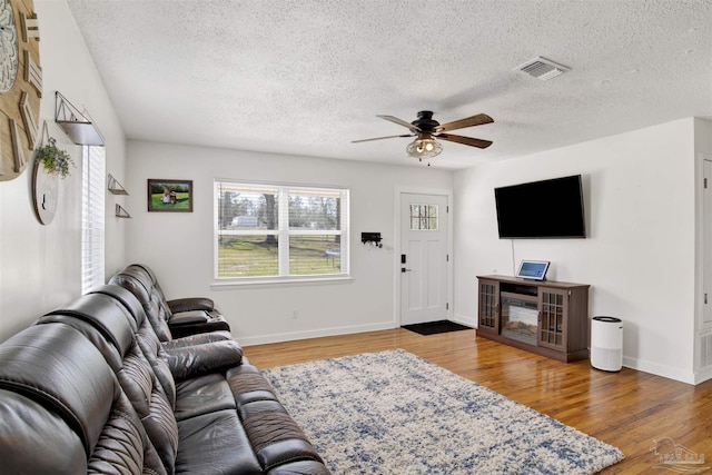 living area featuring visible vents, plenty of natural light, baseboards, and wood finished floors