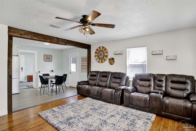 living area with wood finished floors, a healthy amount of sunlight, visible vents, and a textured ceiling