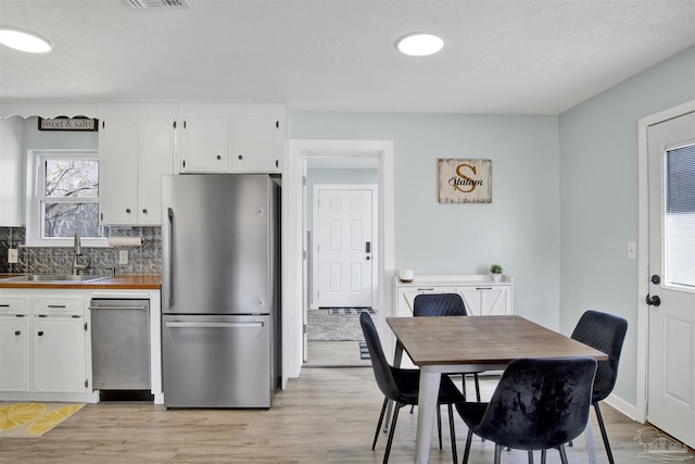 kitchen featuring a sink, white cabinetry, light wood-style floors, and freestanding refrigerator