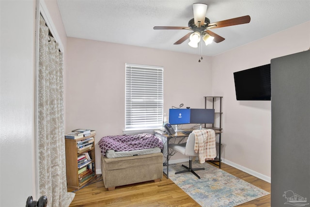 office with baseboards, wood finished floors, and a ceiling fan