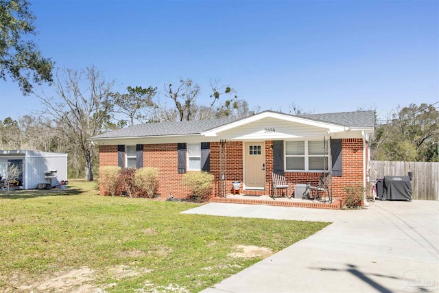 view of front of home with driveway, a front lawn, a porch, fence, and brick siding