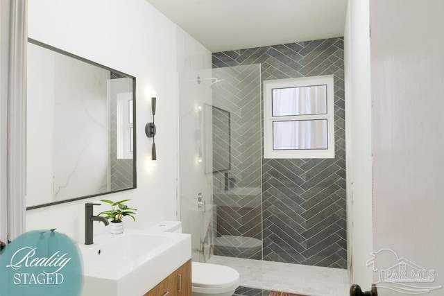 bathroom with tiled shower, toilet, and vanity