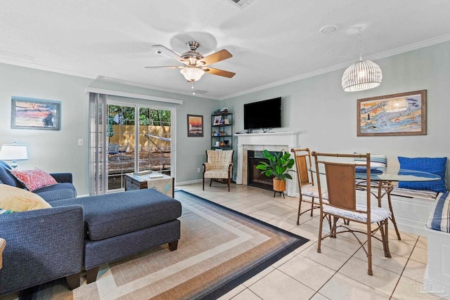 living room featuring ornamental molding, a ceiling fan, light tile patterned floors, and a tile fireplace