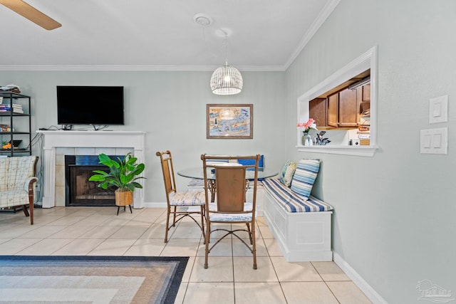 dining room featuring crown molding, baseboards, light tile patterned floors, and a fireplace