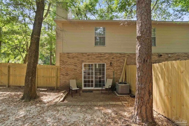 back of property featuring central air condition unit, brick siding, fence, and a chimney