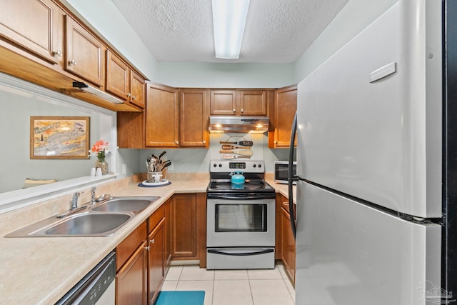 kitchen featuring a sink, under cabinet range hood, brown cabinets, and stainless steel appliances