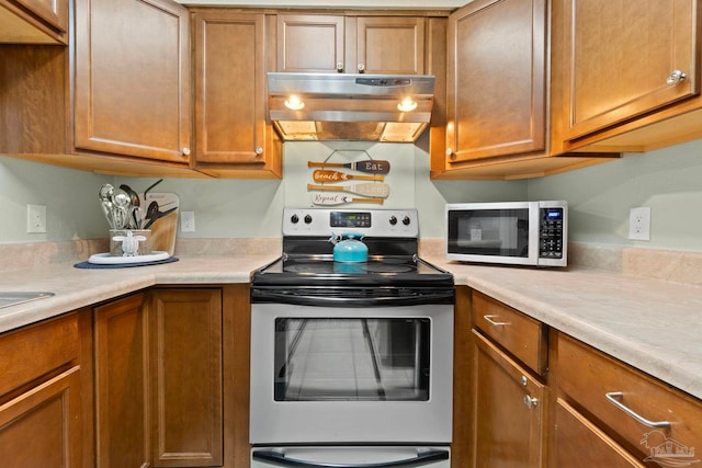 kitchen with under cabinet range hood, brown cabinets, stainless steel electric stove, and white microwave