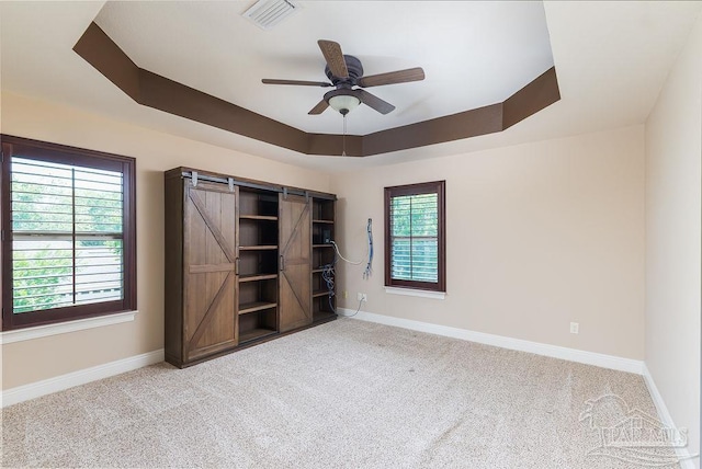 4513 River Ranch Rd, Milton, FL 32583 - unfurnished bedroom featuring a raised ceiling, carpet, a barn door, and ceiling fan