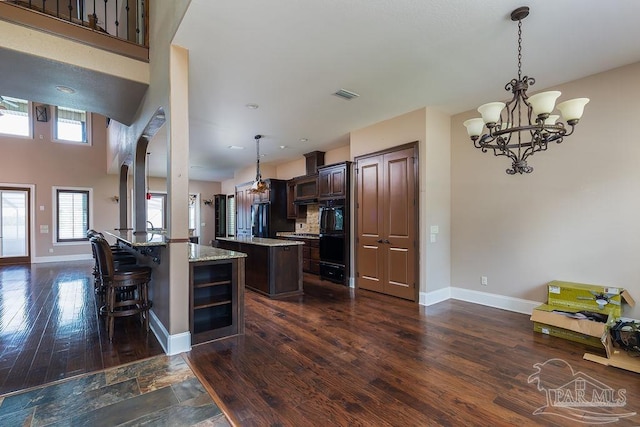 4513 River Ranch Rd, Milton, FL 32583 - kitchen with fridge, dark brown cabinetry, a chandelier, a peninsula, and hanging light fixtures