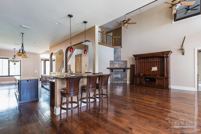 4513 River Ranch Rd, Milton, FL 32583 - kitchen with ceiling fan, dark wood-style floors, a glass covered fireplace, a breakfast bar, and lofted ceiling