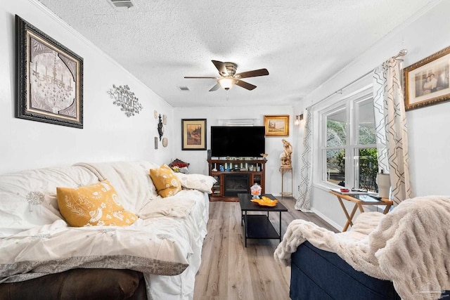 living room featuring light wood-type flooring, a textured ceiling, and ceiling fan