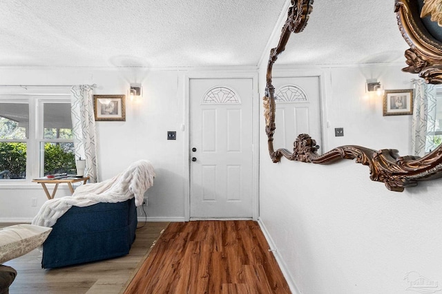 foyer with a textured ceiling, crown molding, and dark wood-type flooring