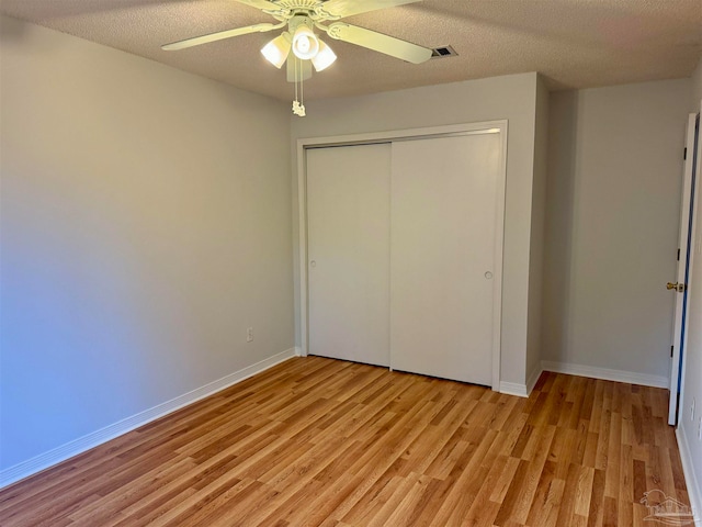 unfurnished bedroom featuring ceiling fan, a closet, light hardwood / wood-style floors, and a textured ceiling