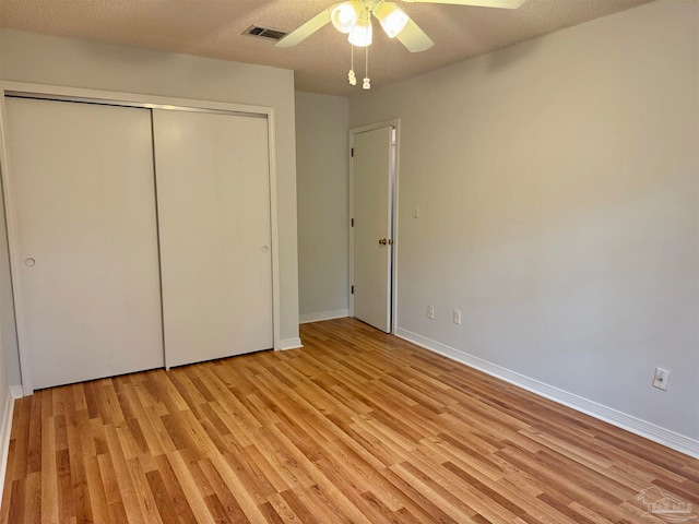 unfurnished bedroom featuring a textured ceiling, light wood-type flooring, a closet, and ceiling fan