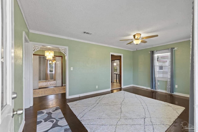 unfurnished bedroom featuring crown molding, multiple windows, dark hardwood / wood-style floors, a textured ceiling, and ceiling fan with notable chandelier